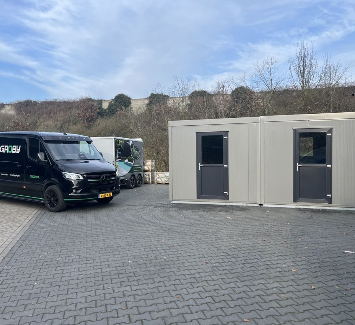 voorkant maatwerk berging houtcomposiet met Groby bus op achtergrond