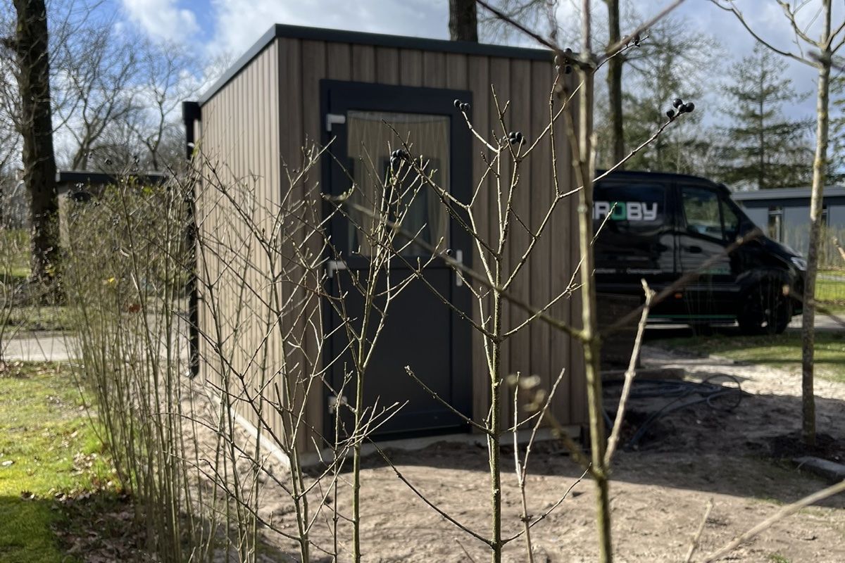 Donkere tuinberging geplaatst in ruime tuin met pad en beplanting